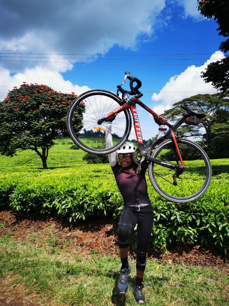 Cyclist lifting their bike at Limuru tea farms during a Kenya Adventure Tour with Wild Pro Adventures