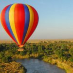 Hot air balloon flying over a river in Maasai Mara National Reserve, Kenya